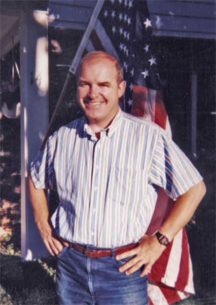 Mike Cronin standing in front of a USA flag